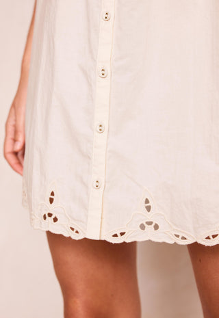 close-up-of-a-cream-colored-eyelet-button-down-dress-with-a-scalloped-hem-worn-by-a-model