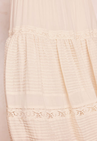close-up-of-a-cream-colored-sheer-tulle-dress-with-horizontal-pleated-detailing-and-delicate-lace-trim