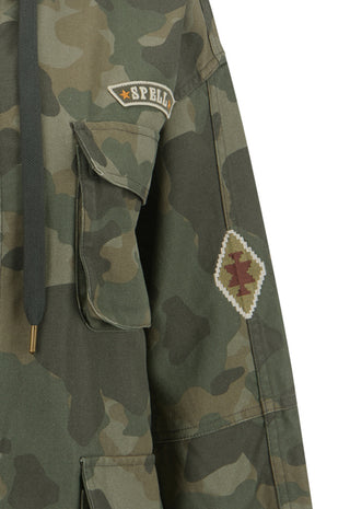 Close-up of a camouflage jacket with a dark drawstring, a flap pocket, a 'SPELL' embroidered patch on the chest, and a diamond-shaped embroidered patch on the sleeve, set against a plain white background.