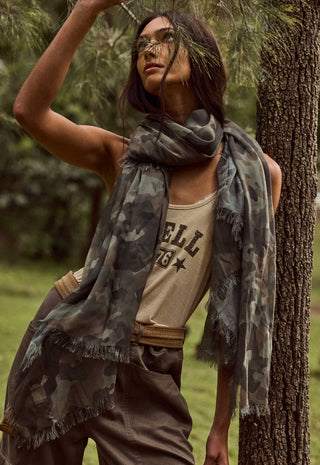 Front view of camo green modal travel scarf with frayed edges, draped loosely around model's neck outdoors